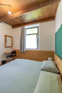 a bedroom with a bed and a window and a desk at La Vrata Gialla in Taipana