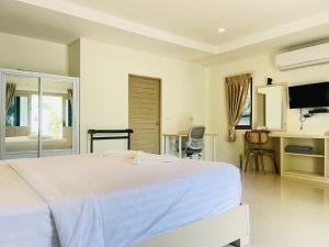 a white bedroom with a large bed and a television at Breeze Bay Villas Koh Phangan in Wok Tum