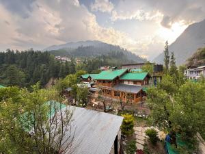 a building with a green roof on a mountain at Non Stop Cafe Hostel & Stay in Manāli