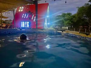 a person in a swimming pool with a building in the background at A Frame house Perú in Lambayeque