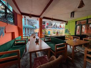 a restaurant with tables and chairs in a room at Non Stop Cafe Hostel & Stay in Manāli
