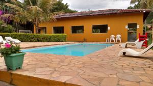 a swimming pool with chairs and a house at Pousada Paraiso pesca esportiva in Serra Negra