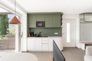 a kitchen with white cabinets and a green wall at Ferienwohnungen Steinegg in Lagundo