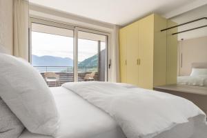 a bedroom with a white bed and a large window at Ferienwohnungen Steinegg in Lagundo