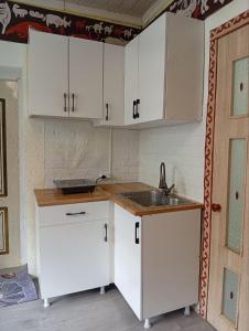 a kitchen with white cabinets and a sink at Guest House Aruuke in Naryn