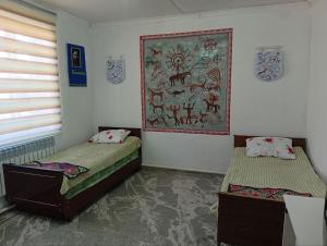 a room with two beds and a painting on the wall at Guest House Aruuke in Naryn