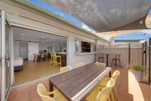 a patio with a wooden table and yellow chairs at Raintree Motel Biloela in Biloela