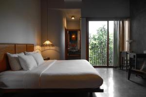 a bedroom with a large white bed and a balcony at De Hué in Hue