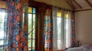 um quarto com cortinas e janelas coloridas e uma cama em Bangalô da Mata em Ilhabela