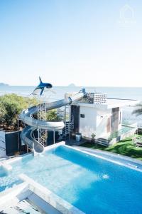 a swimming pool with a water slide in front of a house at Sky Beach Pool Villa Chanthaburi 2 in Laem Sing