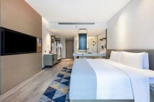 a hotel room with a large bed and a flat screen tv at Wanda Moments Nanchang in Xinjian