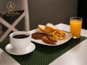 a plate of breakfast food and a cup of coffee and orange juice at Hotel Alcántara Boutique in San Salvador