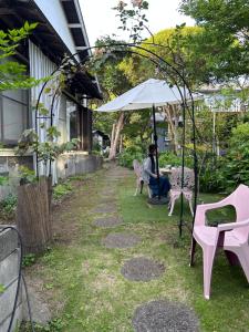 a woman sitting at a table under an umbrella at ＯＫＵＮＯ ＩＥ in Oshima