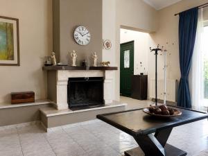 a living room with a fireplace and a clock on the wall at Villa Alexandra Rio Patra in Áyios Vasílios