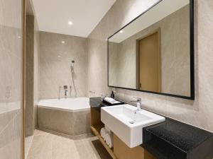 a bathroom with a sink and a tub and a mirror at Prime Plaza Hotel Mataram in Mataram +17 photos