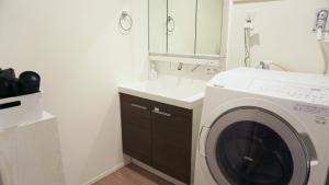 a bathroom with a washing machine and a sink at Sakura View Nagoya Stay Hub in Nagoya
