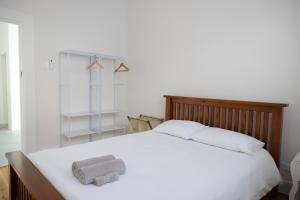 a bedroom with a white bed with two towels on it at Belle Escapes Henley's Coastal Charm in Henley Beach South