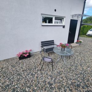 eine Terrasse mit Tisch, Bank und Blumen in der Unterkunft Cozy apartment Sofia in Fjälkinge