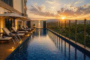 a hotel swimming pool with a sunset in the background at Prime Plaza Hotel Mataram in Mataram
