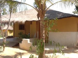 a house with a palm tree in front of it at Campement Le Cormoran in Ndangane