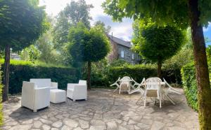 a patio with white chairs and tables and trees at Beauséjour in Calvinet