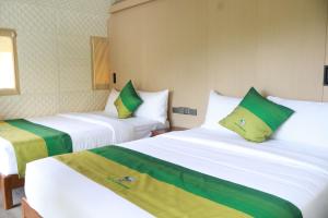 two beds in a room with green and white at The Playground in Baras