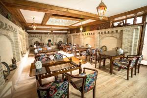 a restaurant with wooden tables and chairs and brick walls at As-Salam Boutique Hotel in Bukhara