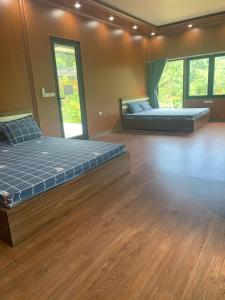 two beds in a large room with wooden floors at Educational Eco Ba Vi in Thủ Pháp