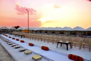 a long line of tables and chairs in front of tents at Big Brand Desert Camp in Jaisalmer