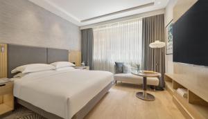 a bedroom with a large white bed and a tv at Hyatt Regency London Olympia in London