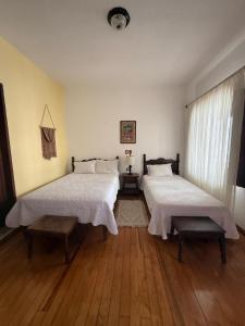 two beds in a room with wooden floors at Hotel Posada San Rafael in Pátzcuaro
