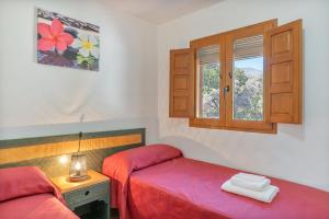 a bedroom with a red bed and a window at Cortijo Corral del Gallo in Órgiva +29 photos