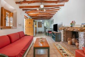 a living room with a red couch and a fireplace at Cortijo Corral del Gallo in Órgiva