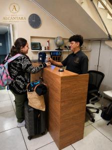 a man and a woman standing at a counter at Hotel Alcántara Boutique in San Salvador