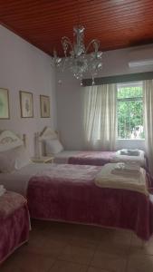 a bedroom with two beds and a chandelier at Nineta's House Sea View near the Airport in Artemida