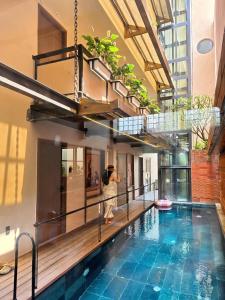 a person standing next to a swimming pool in a building at REFUEL NEST Boutique Hotel in Danang