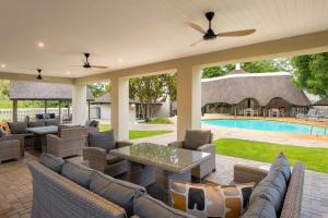 a patio with couches and a table and a pool at Protea Hotel by Marriott Oudtshoorn Riempie Estate in Oudtshoorn