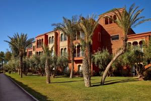 a large building with palm trees in front of it at Delta Hotels by Marriott Marrakech Eden Andalou in Marrakesh