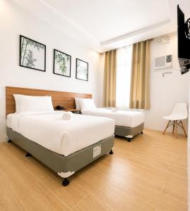 a hotel room with two beds and a chair at Bambu Suites in Puerto Princesa City