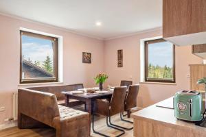 a dining room with a table and chairs and two windows at Ferienwohnung Heimelig im Bayerwald in Haidmühle