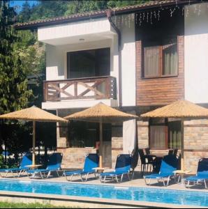 a group of chairs and umbrellas next to a pool at Relax Houses in Ognyanovo