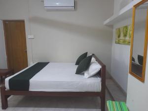 a bedroom with a bed with white sheets and green pillows at The banglow homestay in Anuradhapura