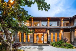 an exterior view of a house with a tree at MOUNT WELL RESORT HOTEL in Lijiang