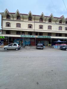 a large building with cars parked in front of it at Hostel Inn in Andijan