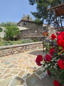 a stone patio with a bench and red roses at Galinos-traditional house B in Eresos +19 photos