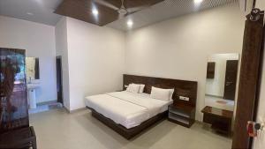 a bedroom with a white bed and a mirror at The Byke Retreat - Laxmi Resort - Pan India Pure Veg Hotel Chain in Matheran