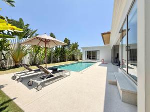 a swimming pool with two lounge chairs and an umbrella at Bali-Style 4 BR Private Pool Villa - Trichada in Phuket