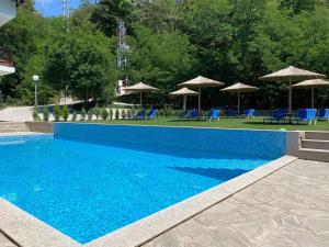 a blue swimming pool with blue chairs and umbrellas at Relax Houses in Ognyanovo