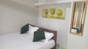 a bedroom with a white bed with green pillows at The banglow homestay in Anuradhapura