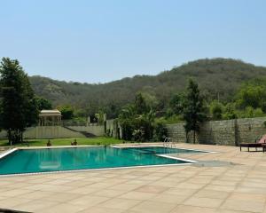a swimming pool in a yard with a stone wall at WelcomHeritage Mount Valley Resort Ranthambore in Sawāi Mādhopur